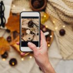 Instagram photography blogging concept. hand holding phone taking photo of stylish winter flat lay. cozy mood autumn.